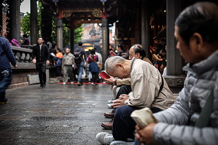 focus photography of man sitting down while praying in front of temple thumbnail