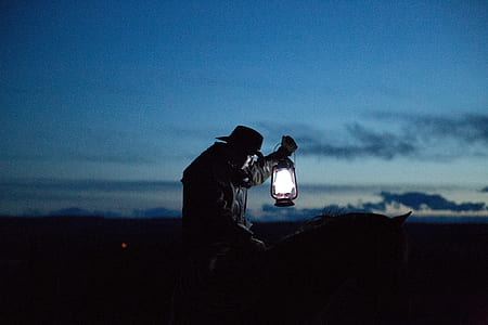 silhouette photograph of person holding kerosene lamp thumbnail