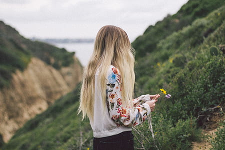 woman wearing white and red long-sleeved shirt holding yellow flower thumbnail