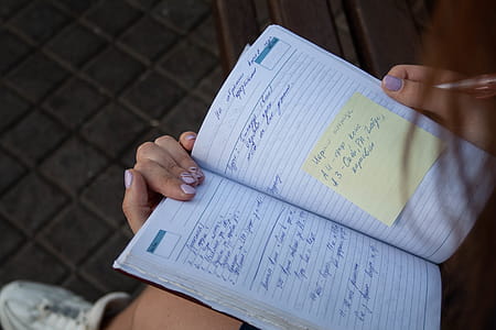 Person Holding Ruled Ntoebook With Yellow Sticky Note thumbnail