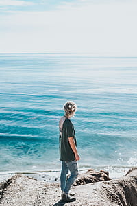 woman in black shirt standing near body of water looking at sea during daytime thumbnail