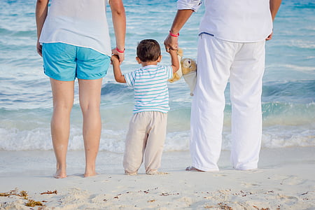 toddler in between man and woman near body of water thumbnail