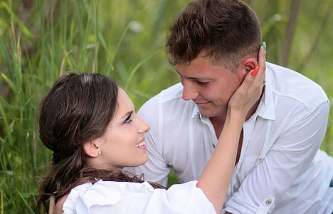 man and woman in white tops at the grass looking at each other thumbnail
