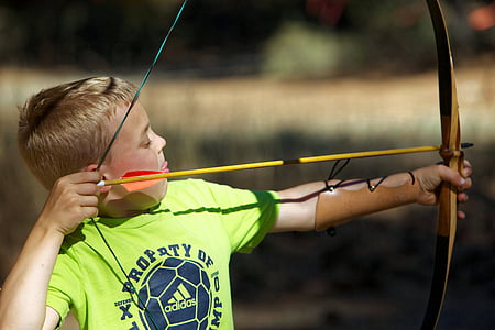 selective focus photography of boy shooting arrow on bow during day thumbnail