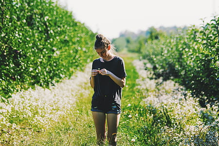 woman in black crew-neck top looking flower thumbnail
