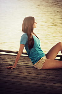 woman wearing blue v-neck shirt sitting on dock thumbnail