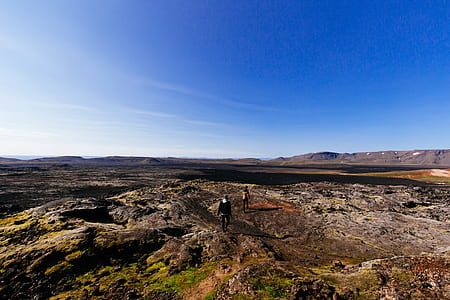 two person walking on mountain peak under blue sky thumbnail