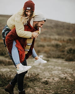 woman piggyback riding on man walking during daytime thumbnail
