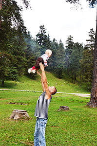 man lifting his child in grass field thumbnail