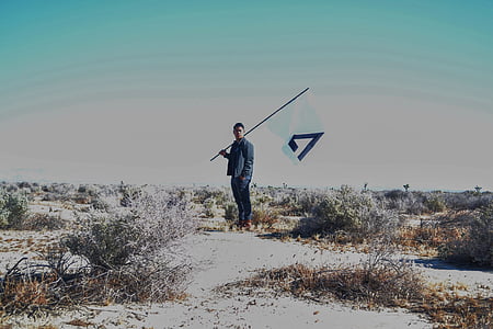 man wearing black jacket standing on open field during daytime thumbnail