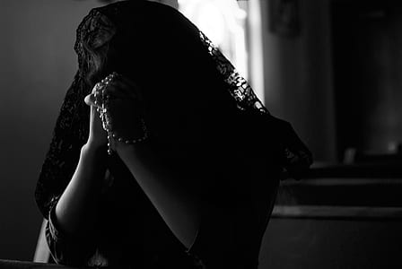 woman praying while holding rosary thumbnail