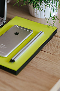 Silver Acer laptop, a white Apple iPhone and a notepad on a wooden desk thumbnail