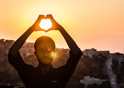 Person Making Heart Shape With His Hand During Sunset thumbnail