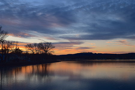 low light photography of body of water under cloudy sky thumbnail