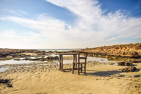 brown wooden table and chair on shore at daytime thumbnail
