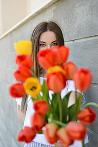 woman in white top holding red and yellow tulips thumbnail