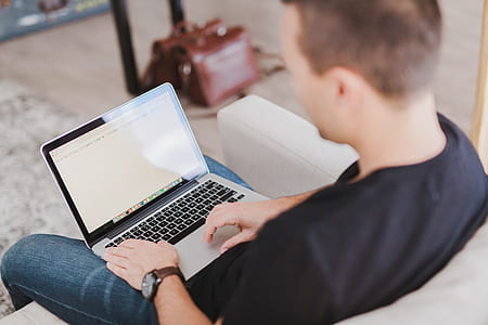 person sitting on gray sofa with MacBook Pro thumbnail