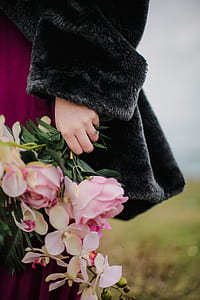 person wearing gray fur coat holding pink and white flowers thumbnail