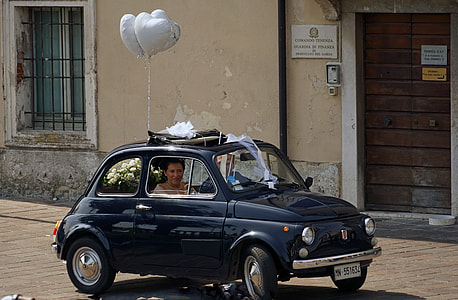 two people inside blue FIAT 500 with heart balloons near building thumbnail
