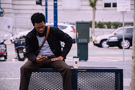 Man Wearing Black Bomber Jacket And Holding Smartphone thumbnail
