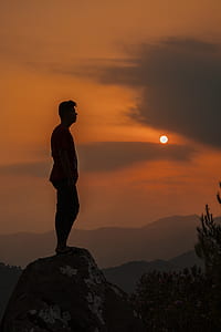 silhouette of man standing on mountain cliff thumbnail