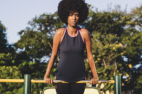 Woman Wearing Black Tank Top With Pink Trim on Yellow Metal Handrail thumbnail