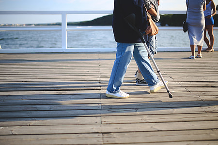 man walking on bridge with crutch during daytime thumbnail