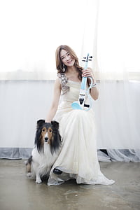 smiling woman holding blue string guitar beside rough collie thumbnail