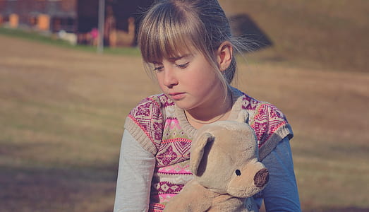 girl holding brown bear plush toy thumbnail