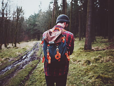 man wearing blue and brown backpack standing in forest thumbnail