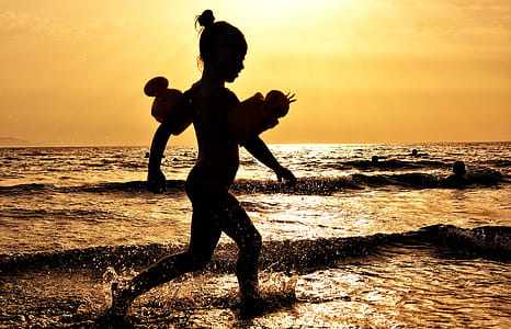 Silhouette of Girl Running on the Seashore during Golden Hour thumbnail