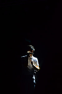portrait photography of man in black and white striped shirt holding microphone stand thumbnail