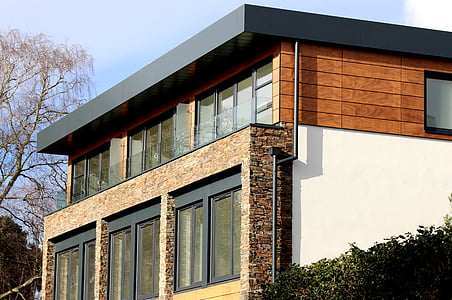 brown and white two-storey house in between hedge and withered tree thumbnail