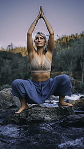 female doing yoga position on top of river rock thumbnail