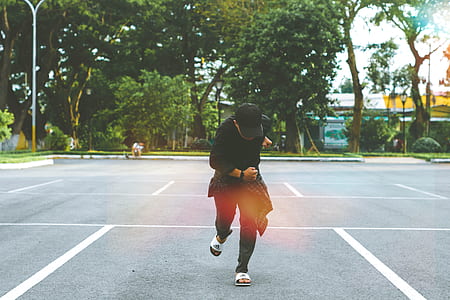 person in black cap, t-shirt, and pants standing on parking spot thumbnail