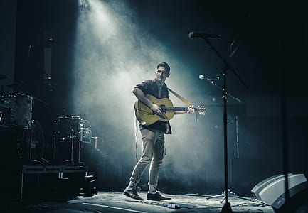 man playing acoustic guitar on stage thumbnail
