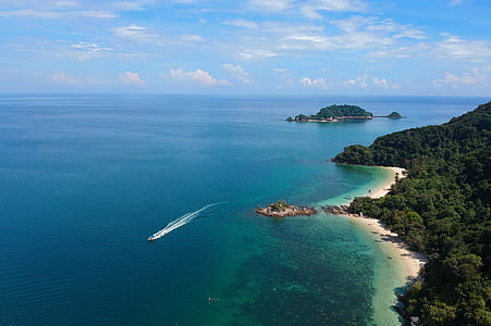 Aerial View of White Boat Traveling Near Green Island thumbnail