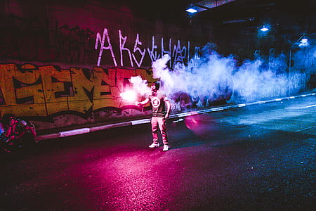 man holding sparkler while standing on street thumbnail