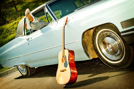 brown acoustic guitar leaning on blue vehicle thumbnail