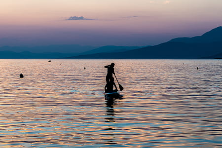 silhouette photo of person paddling board on body of water thumbnail