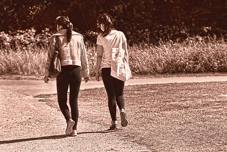 grayscale photo of two women walking near grass thumbnail
