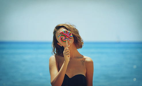 woman in black strapless top holding lollipop thumbnail