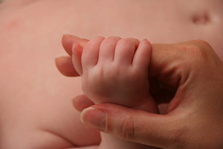 baby gripping adult's hand thumbnail