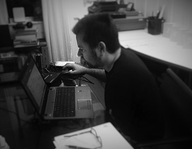grayscale photo of man sits facing laptop thumbnail