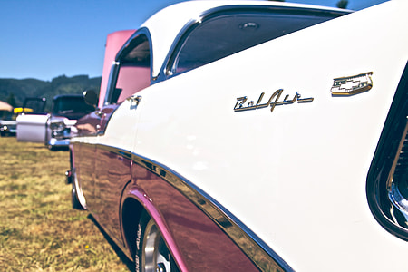 white and red vintage car parked on green grass thumbnail