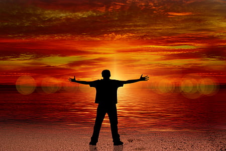 silhouette photo of man facing sun and body of water thumbnail