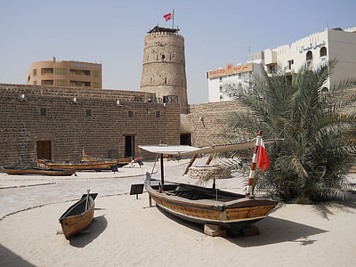 two brown wooden boats on white sand surrounded by grey brick wall and watch tower at daytime thumbnail