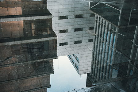black glass reflecting buildings during daytime thumbnail
