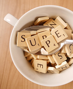 brown wooden scrabble tiles in white ceramic cup thumbnail