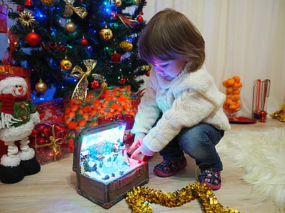 girl beside musical chest and Christmas tree thumbnail